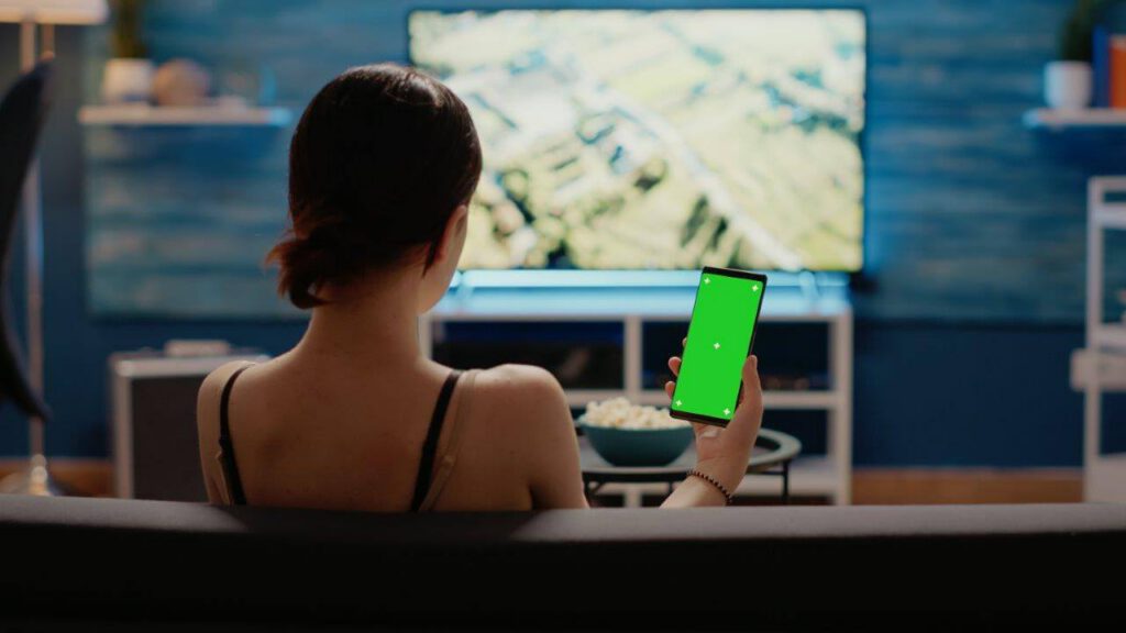 caucasian-woman-holding-mobile-phone-with-green-screen